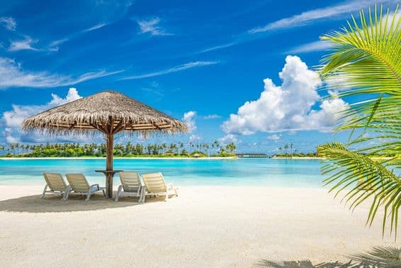 Мальдивский песчаный пляж с зонтиком и шезлонгом.