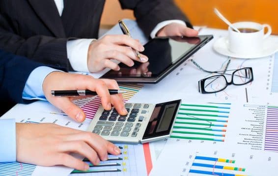 Графики, калькулятор, планшет, усердные руки изучают данные.