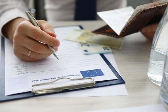 Человек с паспортом, вводящий личные данные в заявлении на получение шенгенской визы.