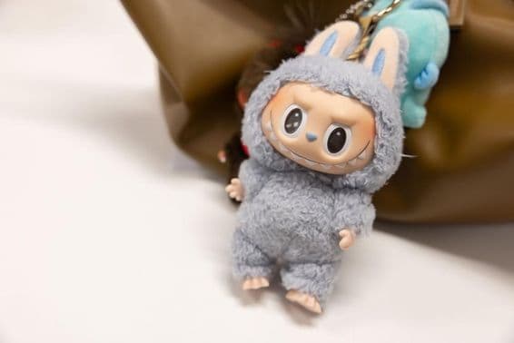 Вид на знаменитый Popmart Labubu на сумке женщины.