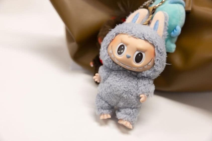 Вид на знаменитый Popmart Labubu на сумке женщины.