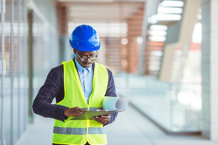 Молодой инженер-строитель анализирует бумажную статистику.