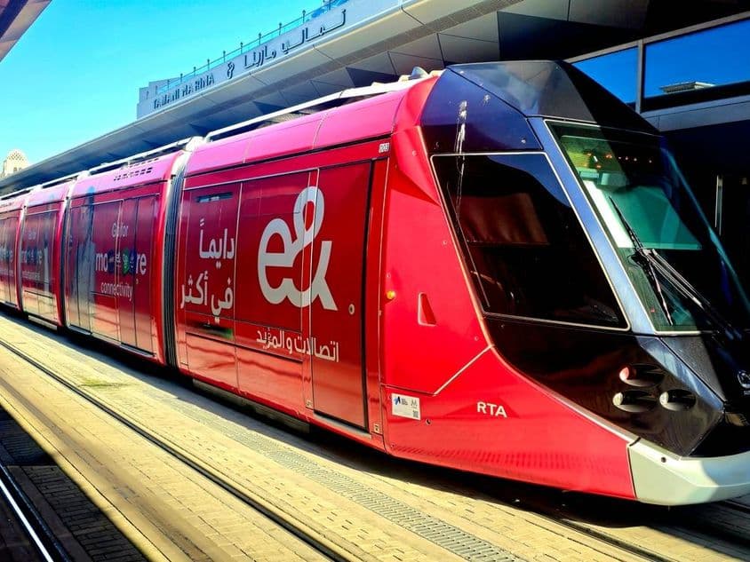 Красный трамвай, припаркованный на платформе с большими окнами и элегантным дизайном.