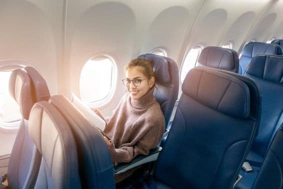 Азиатская женщина читает журнал в самолёте.