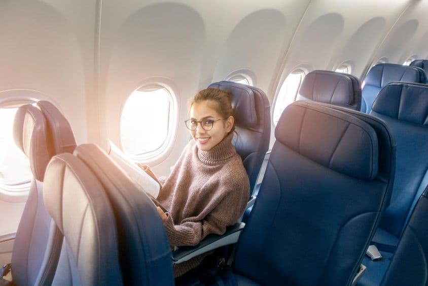 Азиатская женщина читает журнал в самолёте.