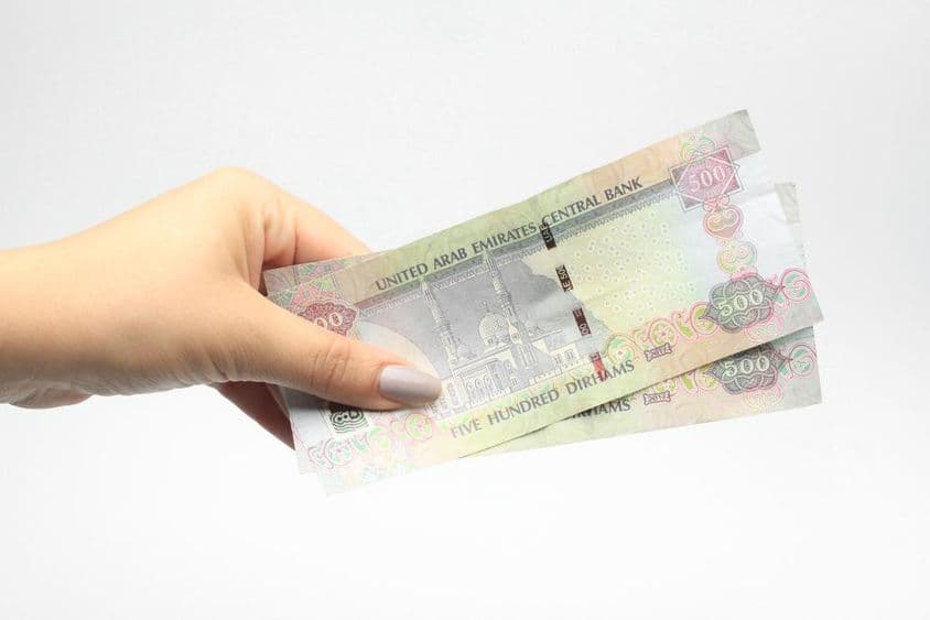 500 дирхам в руке женщины.