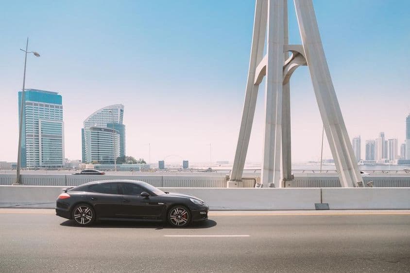 Черный Porsche Panamera движется по улице в Дубае.