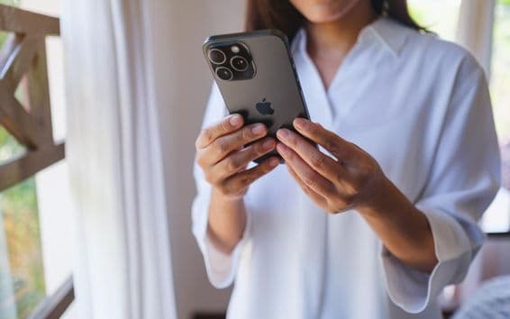 Женщина использует iPhone 15 Pro Max дома.