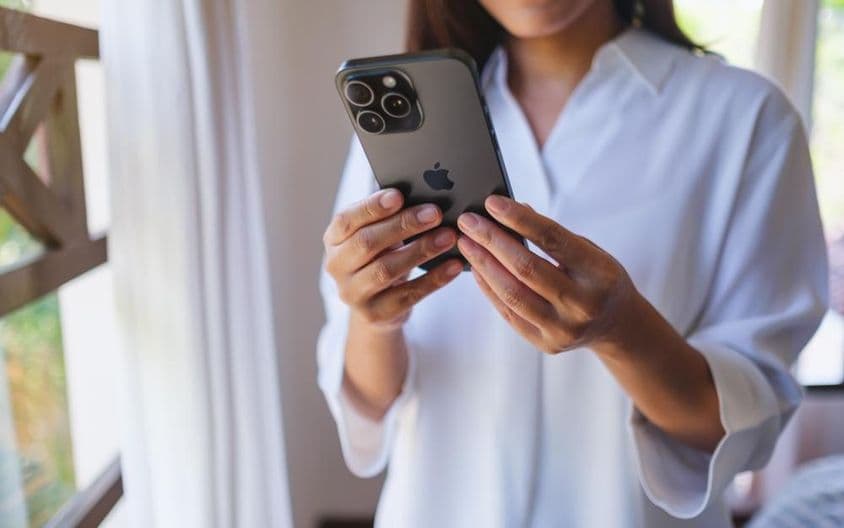 Женщина использует iPhone 15 Pro Max дома.