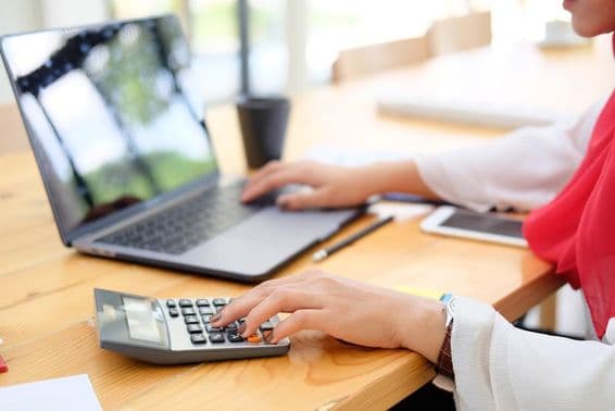 Работница в Дубае подсчитывает финансовые данные на калькуляторе.