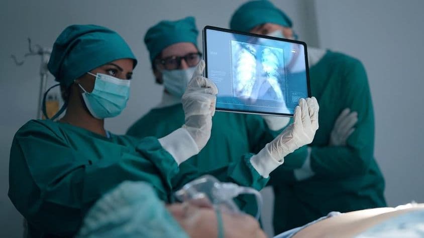 Профессиональная медицинская команда обсуждает и изучает рентгеновский снимок пациента с пневмонией.