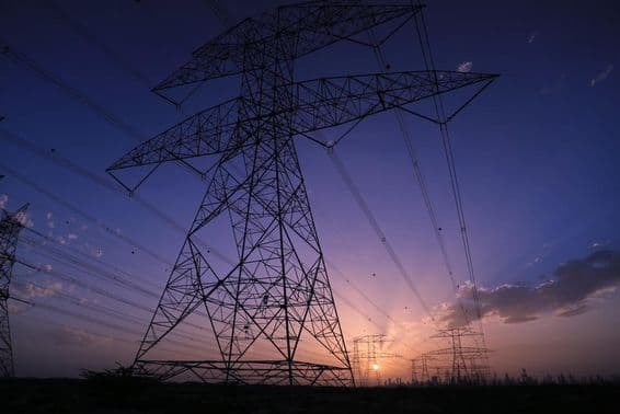 Высоковольтные вышки на фоне заката с видом на городскую панораму Дубая.