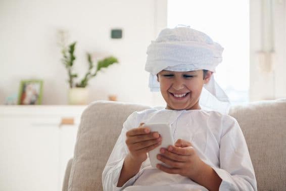 Арабский мальчик использует смартфон дома.