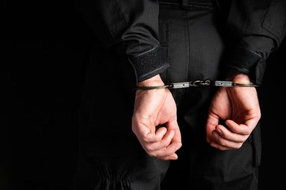 Руки преступника в наручниках.