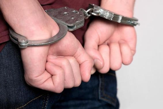 Преступник в наручниках и арестован.