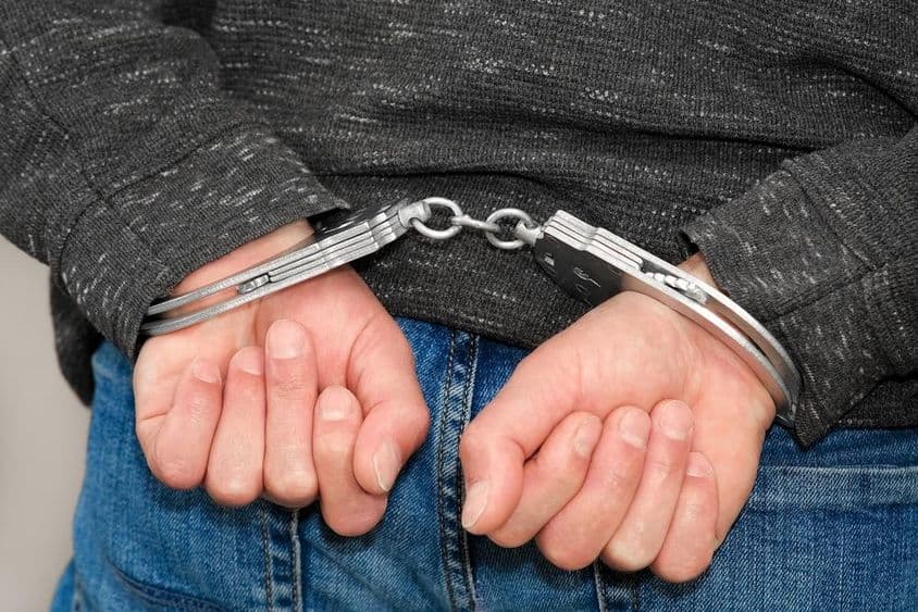 Преступник в наручниках, задержанный за преступления.