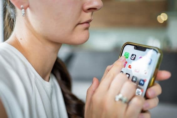 Женщина с iPhone и открытым приложением WhatsApp на экране.