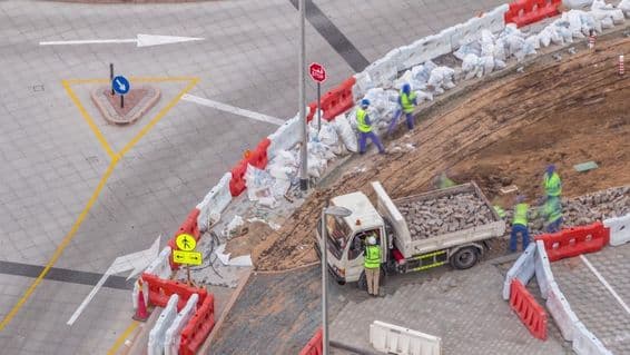 Переход ремонта тротуара с множеством строителей и оборудования, разрушающих тротуар и бетон.