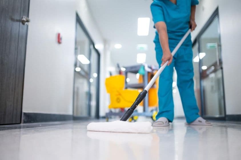 Уборщик моет пол в коридоре.