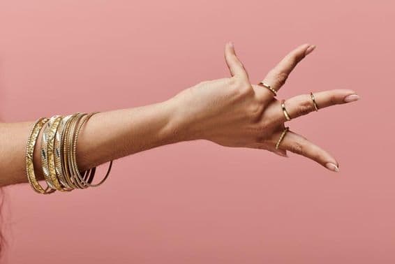 Индийская женщина изящно позирует с золотыми браслетами на запястье.