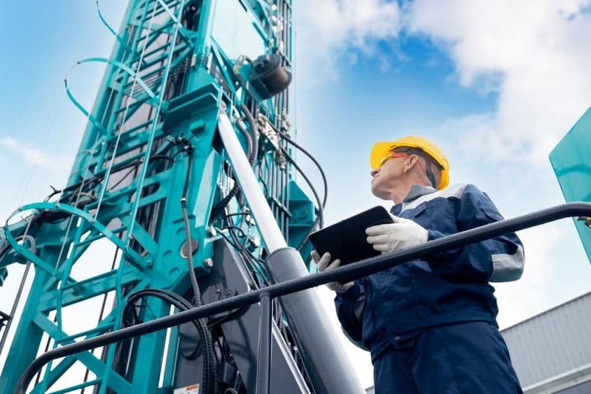 Оператор на платформе управления буровой установкой с цифровым планшетом.