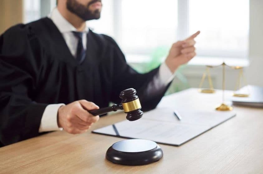 Судья стучит молотком, вынося приговор в зале суда.