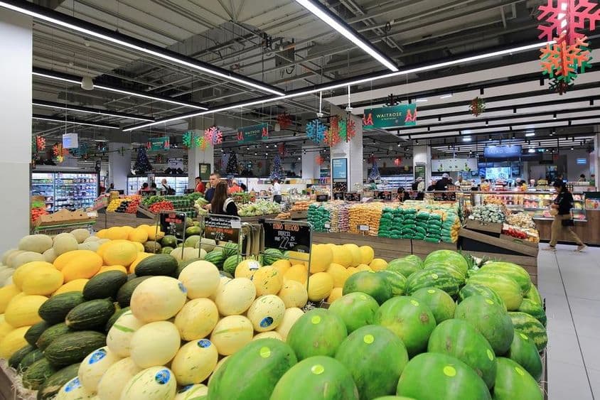 Уложенные зелёные и жёлтые дыни для продажи в супермаркете Дубая.