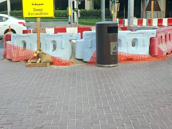 Ремонт дороги окружен пластиковыми барьерами и оранжевой защитной сеткой.