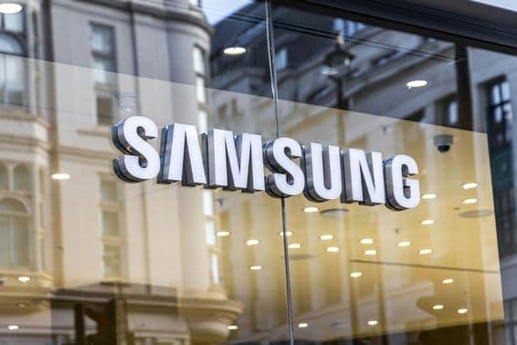 Логотип технологического бренда Samsung на стеклянном окне.