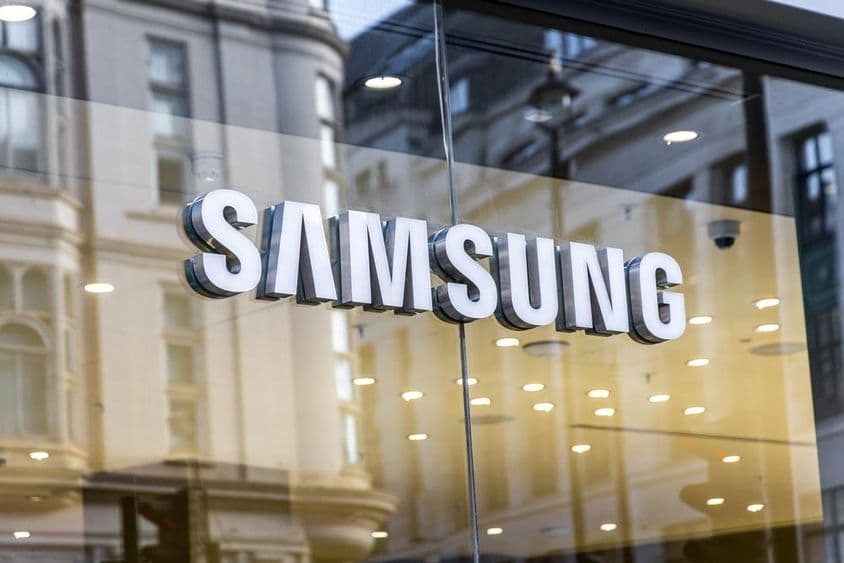 Логотип технологического бренда Samsung на стеклянном окне.