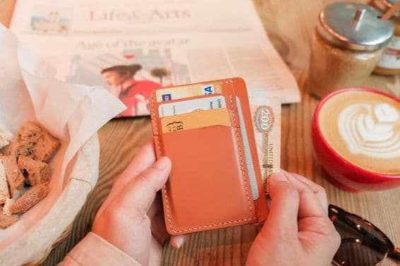 Коричневый кожаный держатель для карт, содержащий удостоверения личности, банковские и кредитные карты.