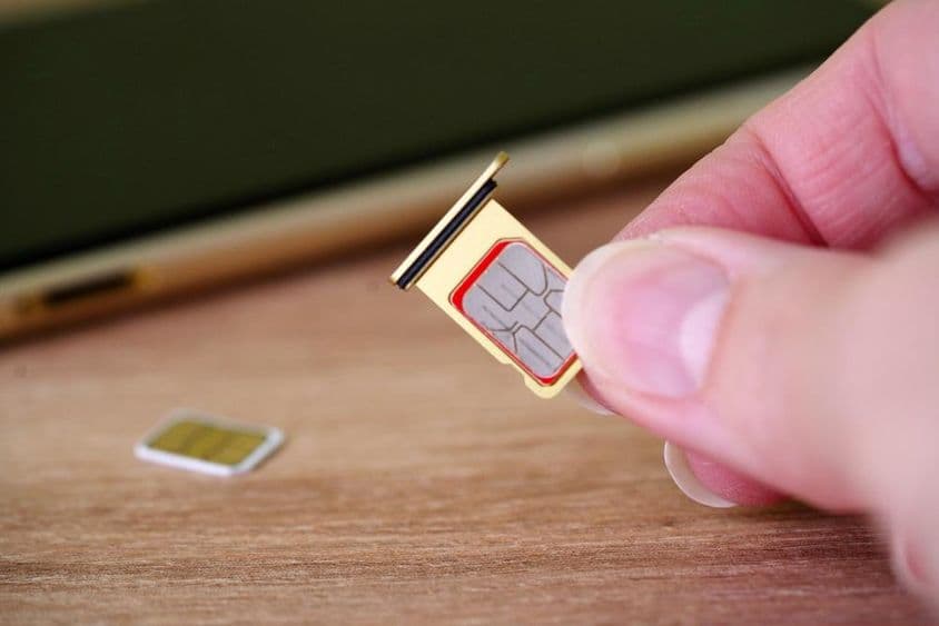 Человек вставляет SIM-карту в заднюю часть мобильного телефона.