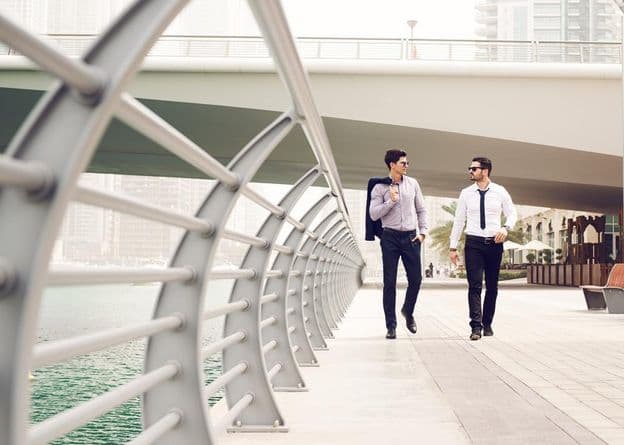 Бизнесмены идут по набережной Дубай-Марины.