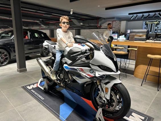 Мальчик в солнечных очках сидит на мотоцикле BMW.