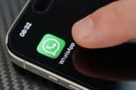 Палец касается иконки приложения WhatsApp