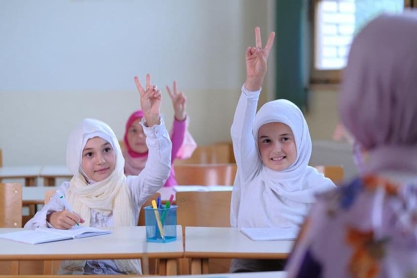 Мусульманские школьники поднимают руки, чтобы ответить на вопросы учителей.