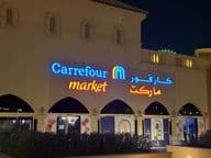 Подсвеченный логотип рынка Carrefour с арабским названием бренда