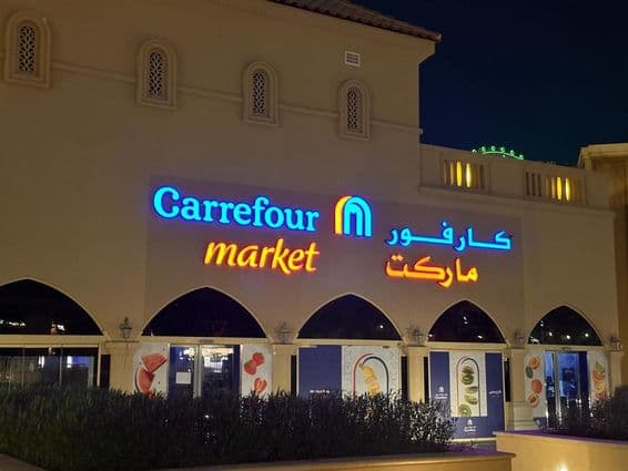 Подсвеченный логотип рынка Carrefour с арабским названием бренда