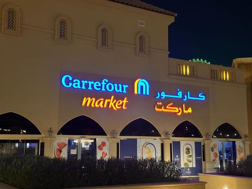 Подсвеченный логотип рынка Carrefour с арабским названием бренда
