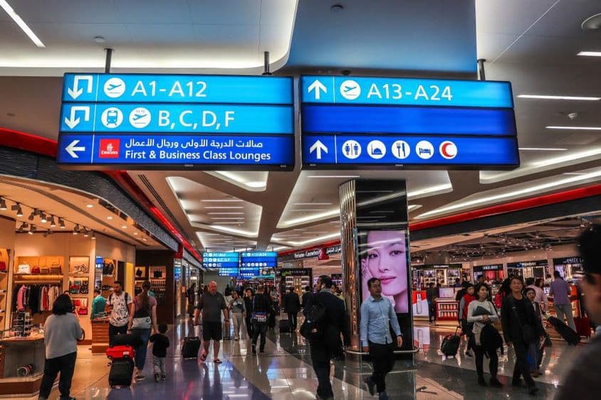 Пассажиры идут в сторону выходов на посадку в Международном аэропорту Дубая